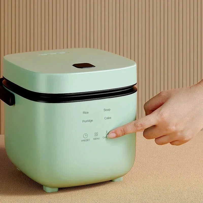 Mini electric rice cooker with green body and black control panel, lid on.