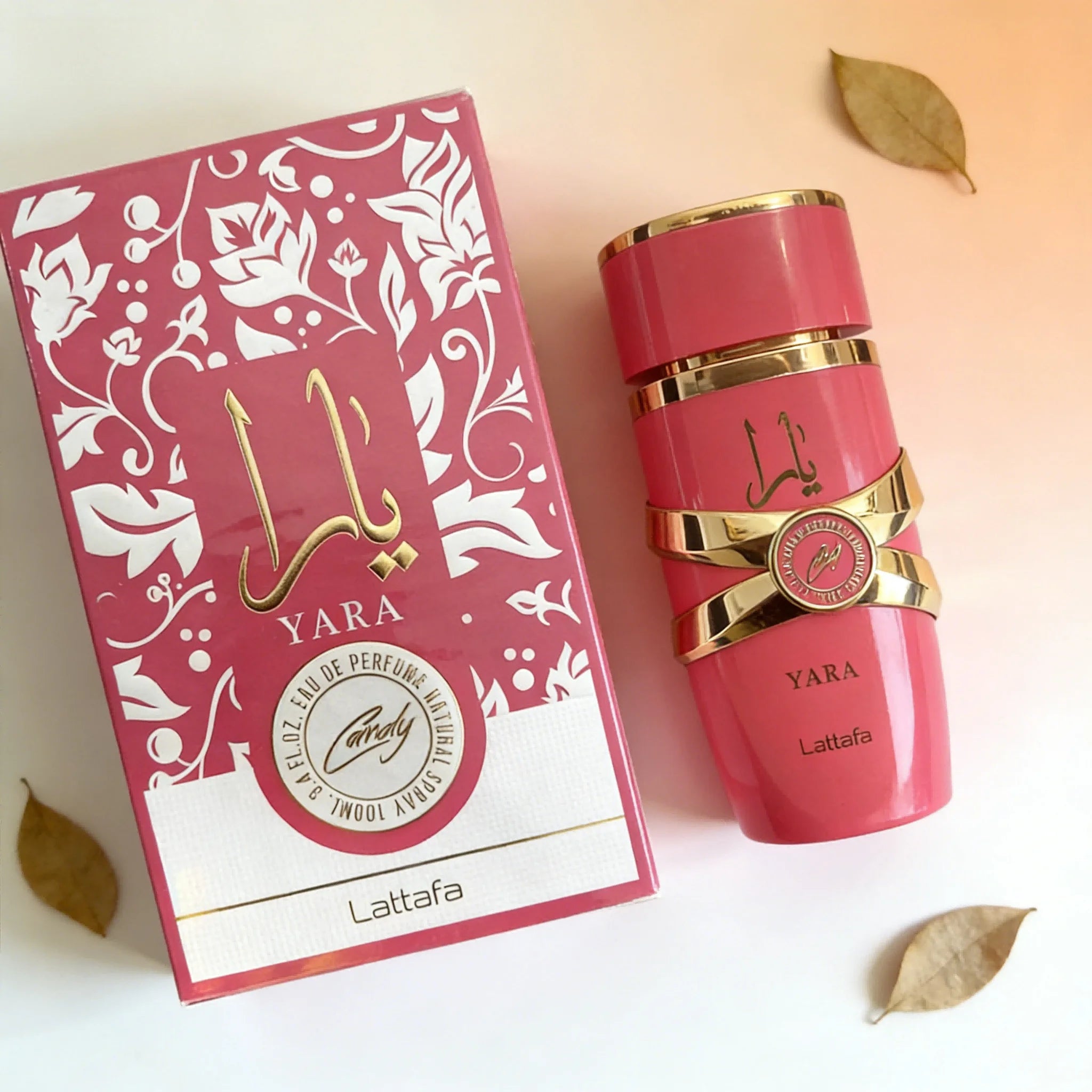 Lattafa Yara Candy perfume bottle and box in vibrant pink with gold accents, floral design, and glossy finish.