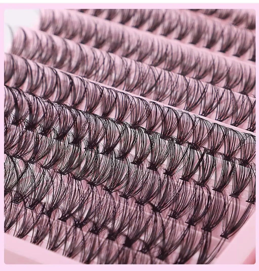 Rows of black DIY cluster lashes arranged on a pink tray, featuring varied lengths for a natural look.