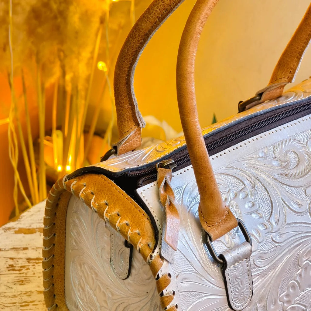 White and tan genuine leather mini duffel with floral tooling, hand-stitched trim, and luxury designer travel style.
