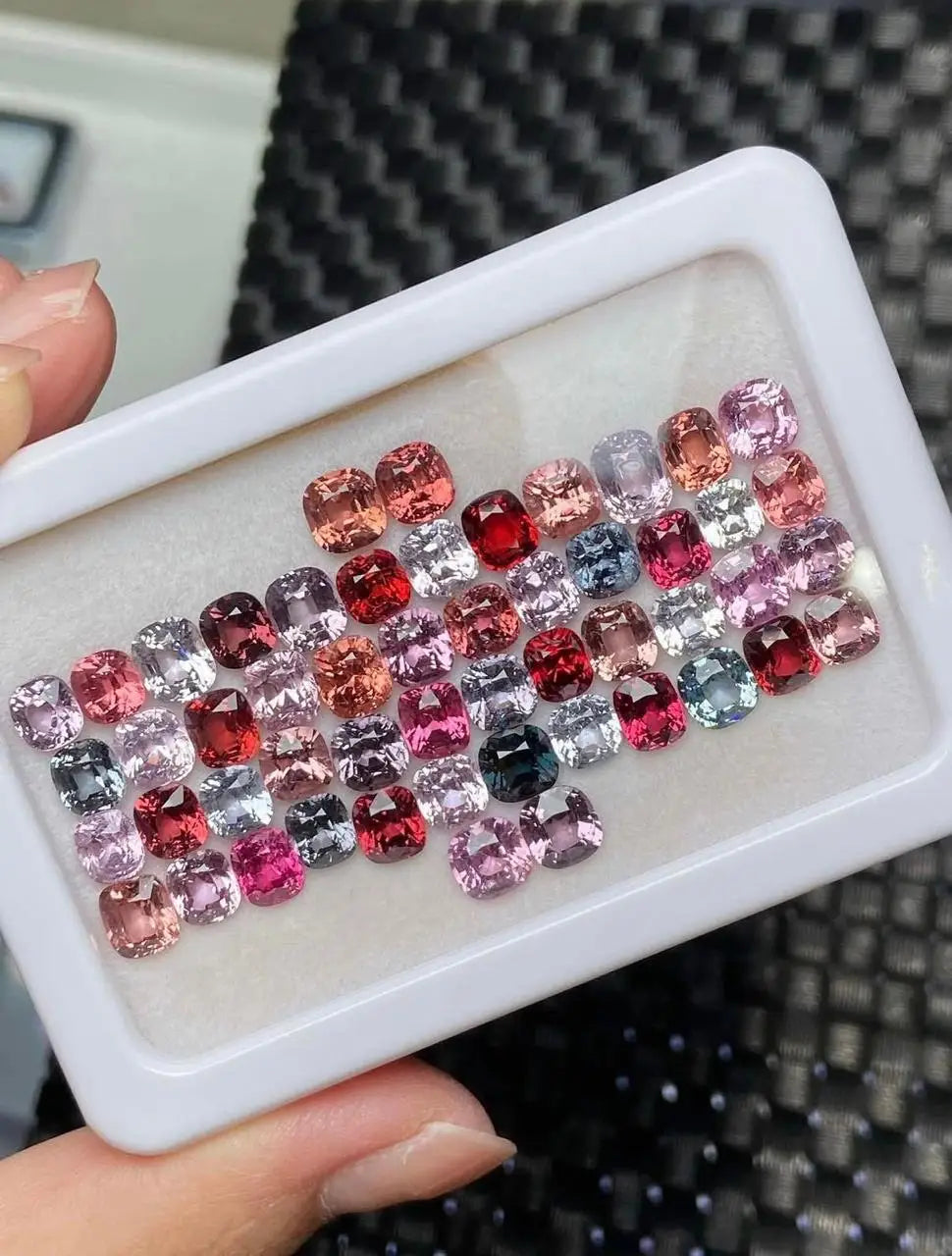 Tray of mixed square-cut gemstones in red, pink, purple, black, and silver tones
