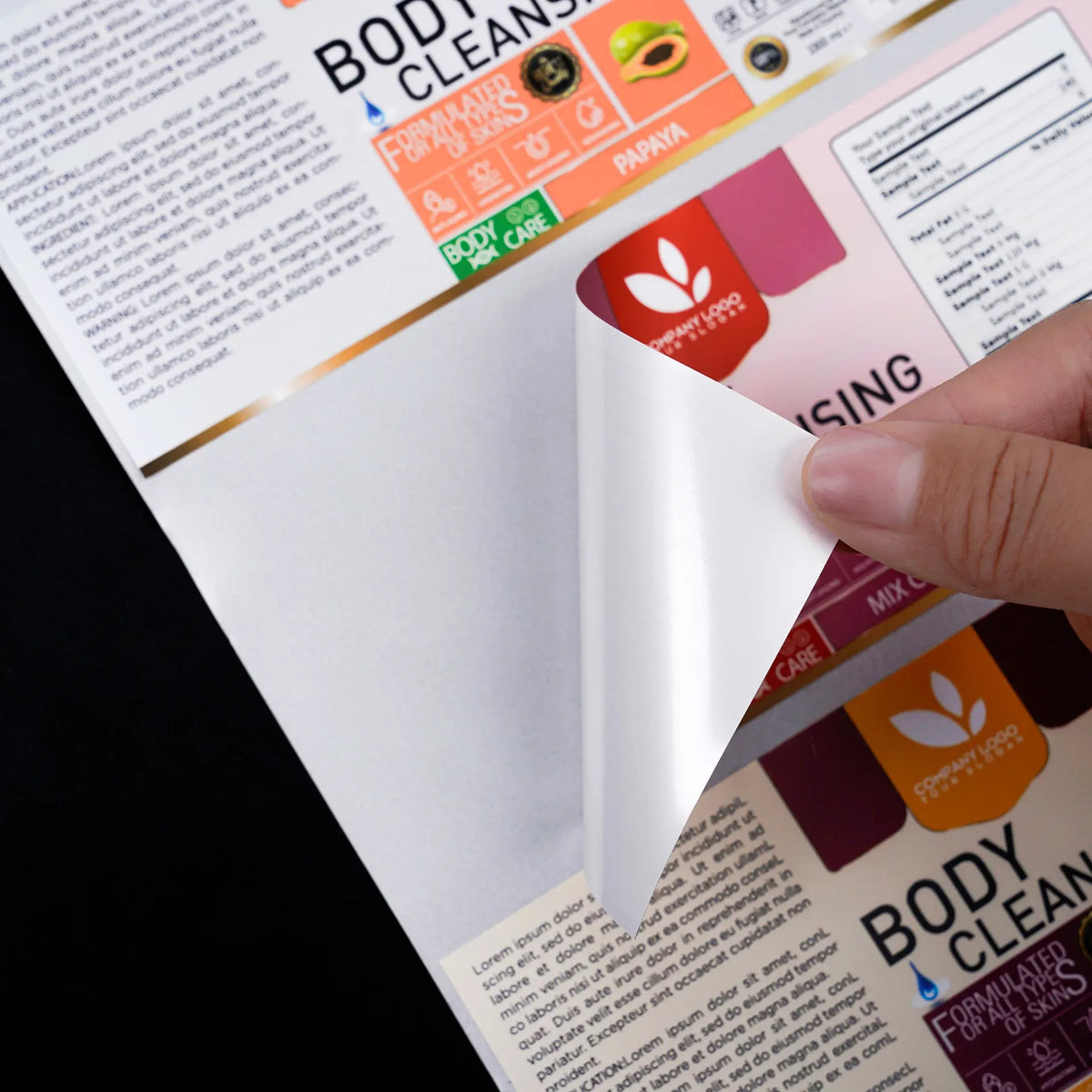 Sheet of printed adhesive labels with body care branding, partially peeled by hand.