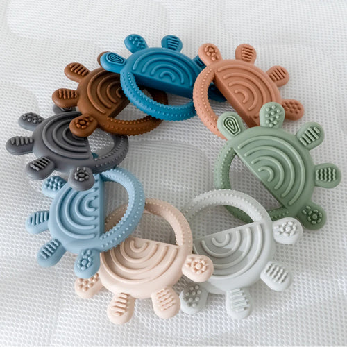 Multi-colored silicone teething rings for baby teething relief in a rainbow shape.