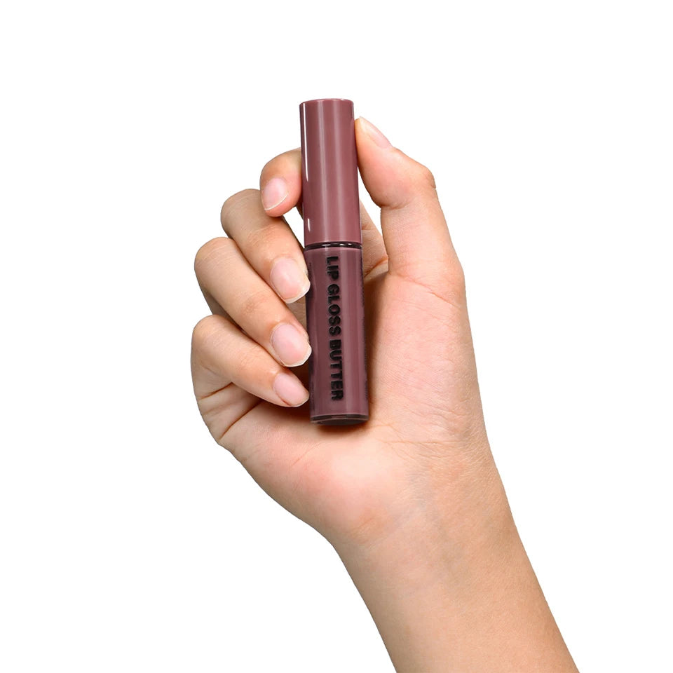 Hand holding a mauve-toned butter lip gloss with a sleek, non-stick mirror finish tube, isolated on white background.
