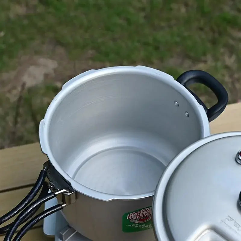 Silver inner pot of a portable pressure cooker with side handles, open lid