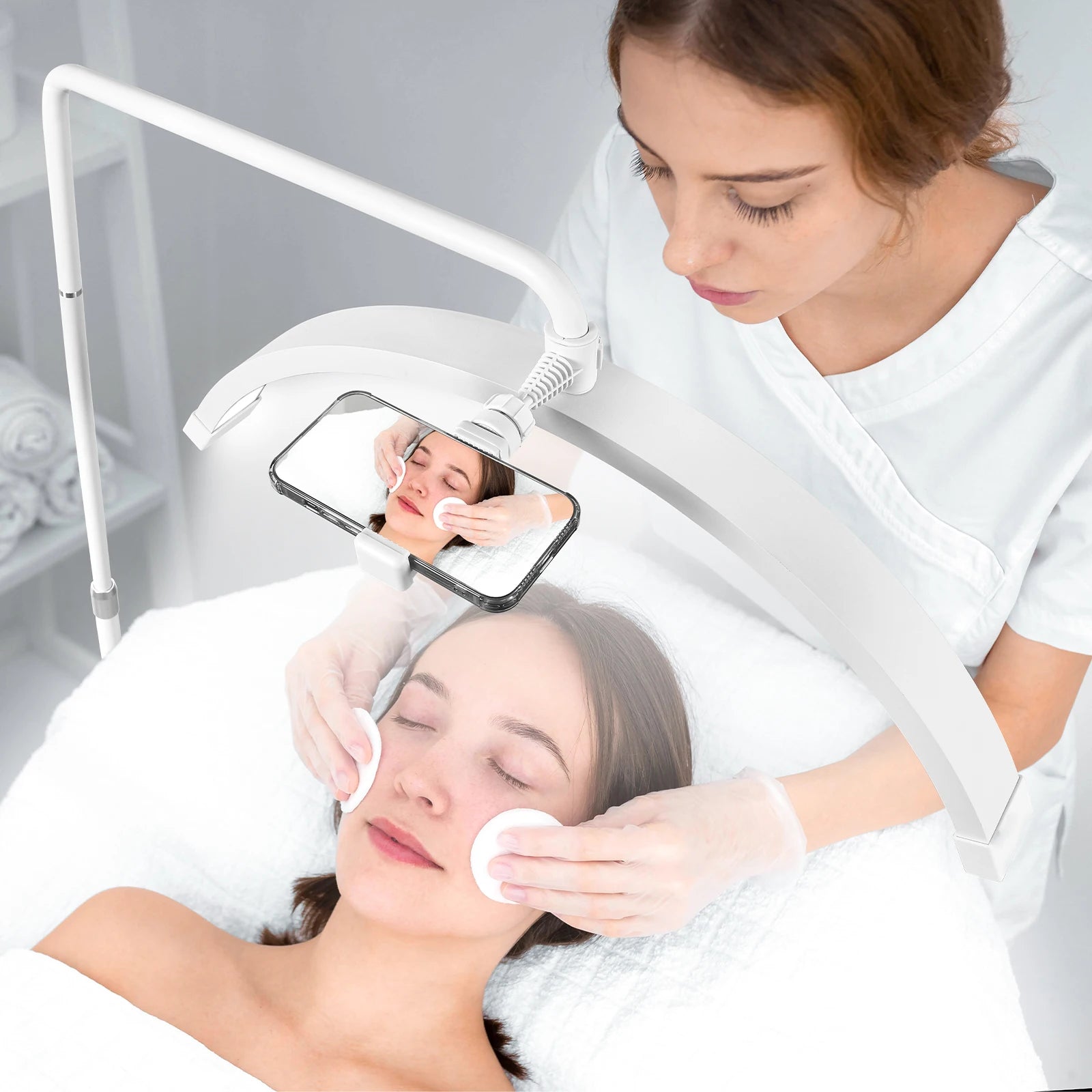 White arched LED salon lamp with an adjustable phone mount for recording esthetician skincare treatments.