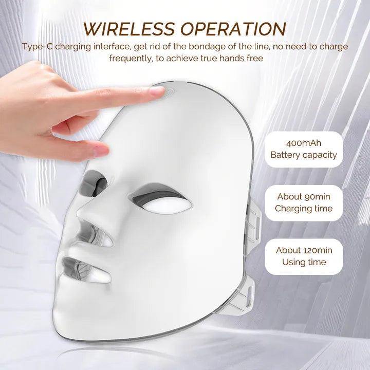 A smooth, white, wireless LED face mask for skincare, shown with a hand touching the top button.