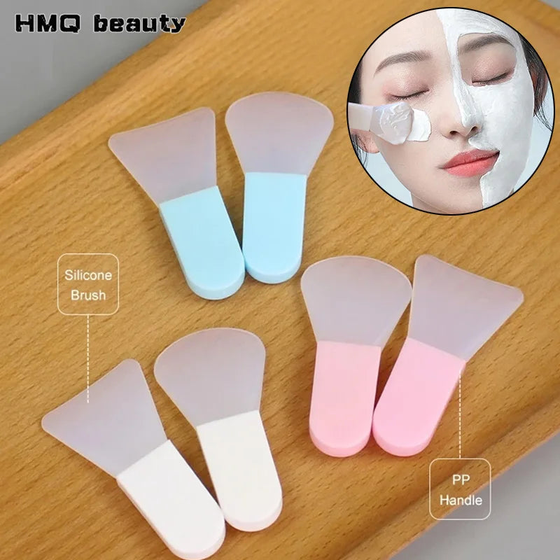 Set of silicone facial mask applicators with flexible translucent heads and colorful blue, pink, and white handles.