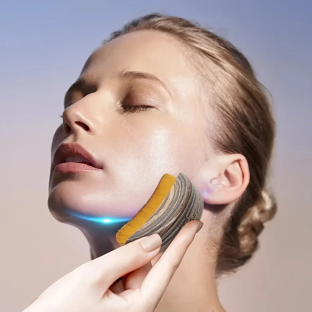 A hand uses a curved, wood-grain handled face brush with yellow bristles to massage a woman’s jawline.