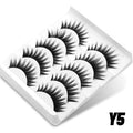 Five pairs of black, wispy 3D mink false lashes with a cat-eye shape, arranged in a white plastic storage tray.