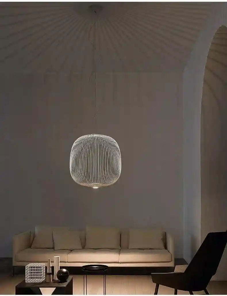 Round, white wire-cage pendant light hanging over a living room sofa, emitting a soft, downward-focused glow.