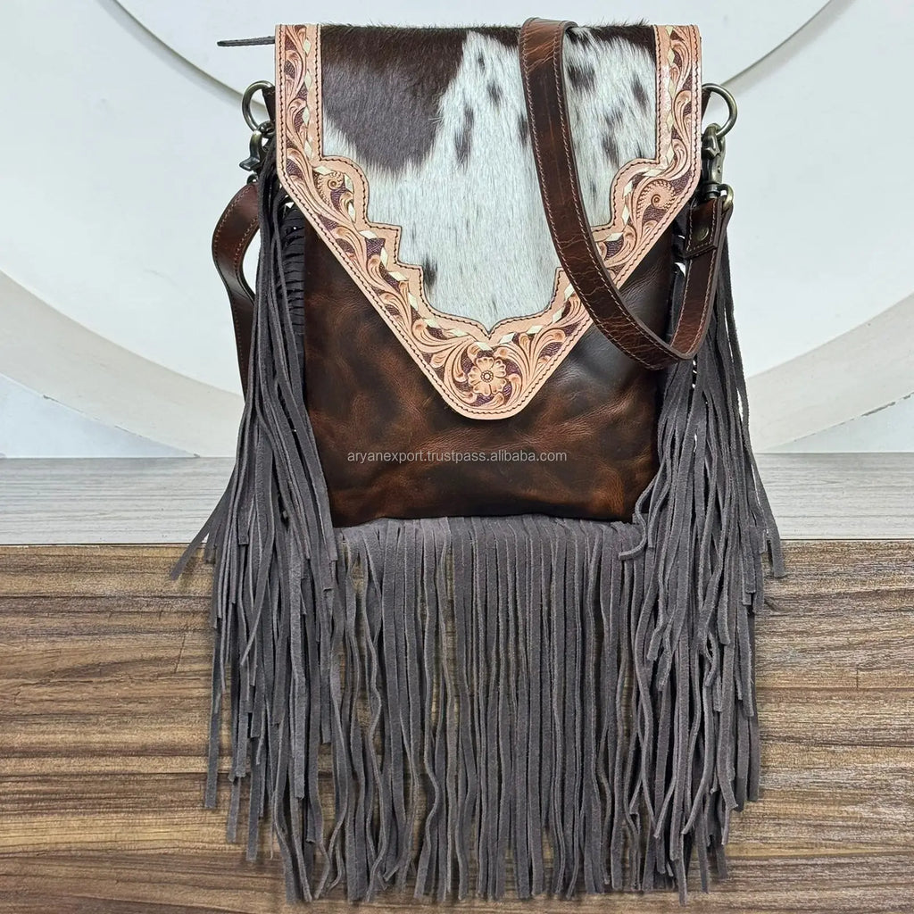 Vintage floral tooled leather fringe crossbody bag with brown cowhide accents. Designer boho style shoulder handbag.