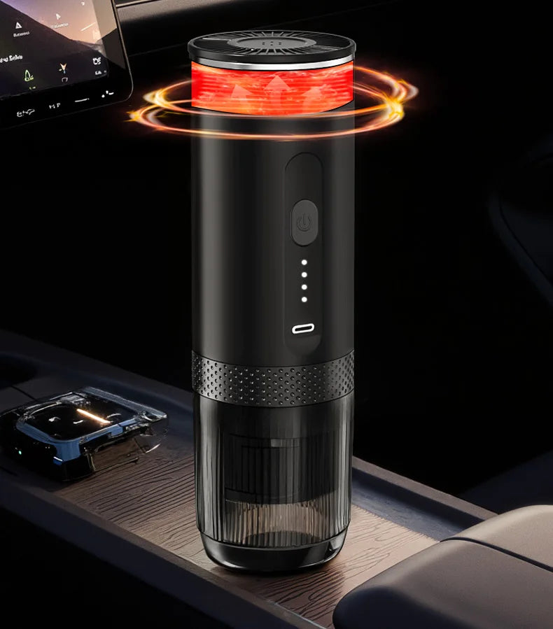 Portable black electric coffee maker with a USB-C port, heating indicator, and clear bottom in a car interior.