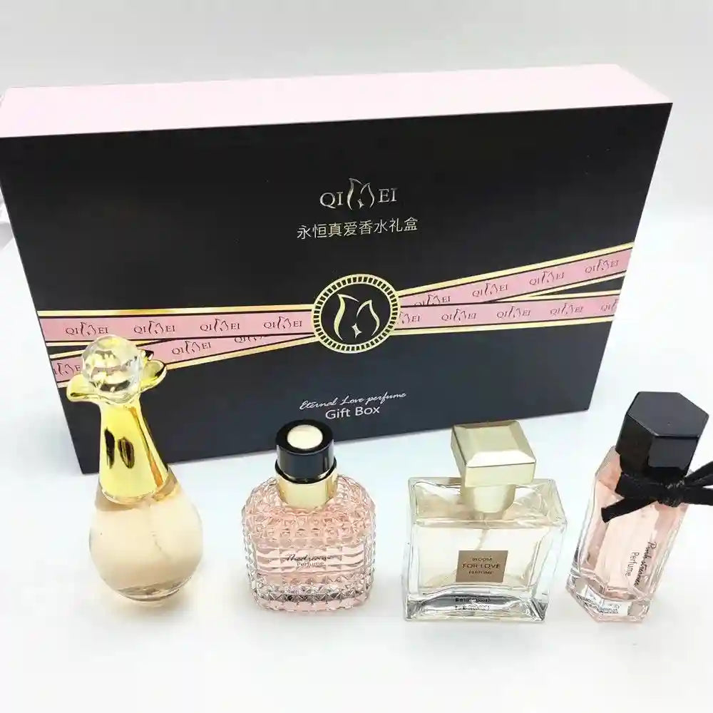 Four varied glass perfume bottles arranged in front of a rectangular black and pink gift box.
