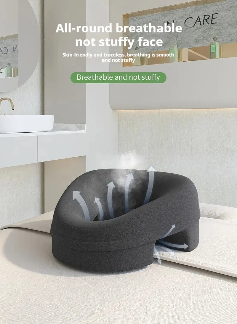 Charcoal gray, U-shaped salon massage pillow on a white table, featuring ventilation arrows and breathable design.