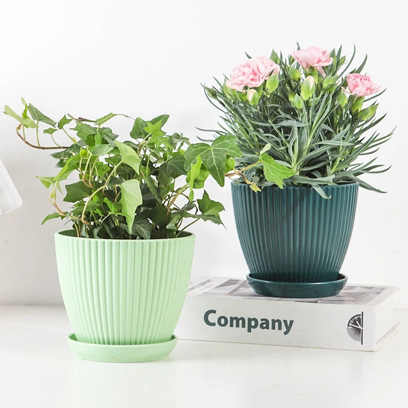 Two ribbed plastic plant pots with trays, mint and dark teal, filled with greenery