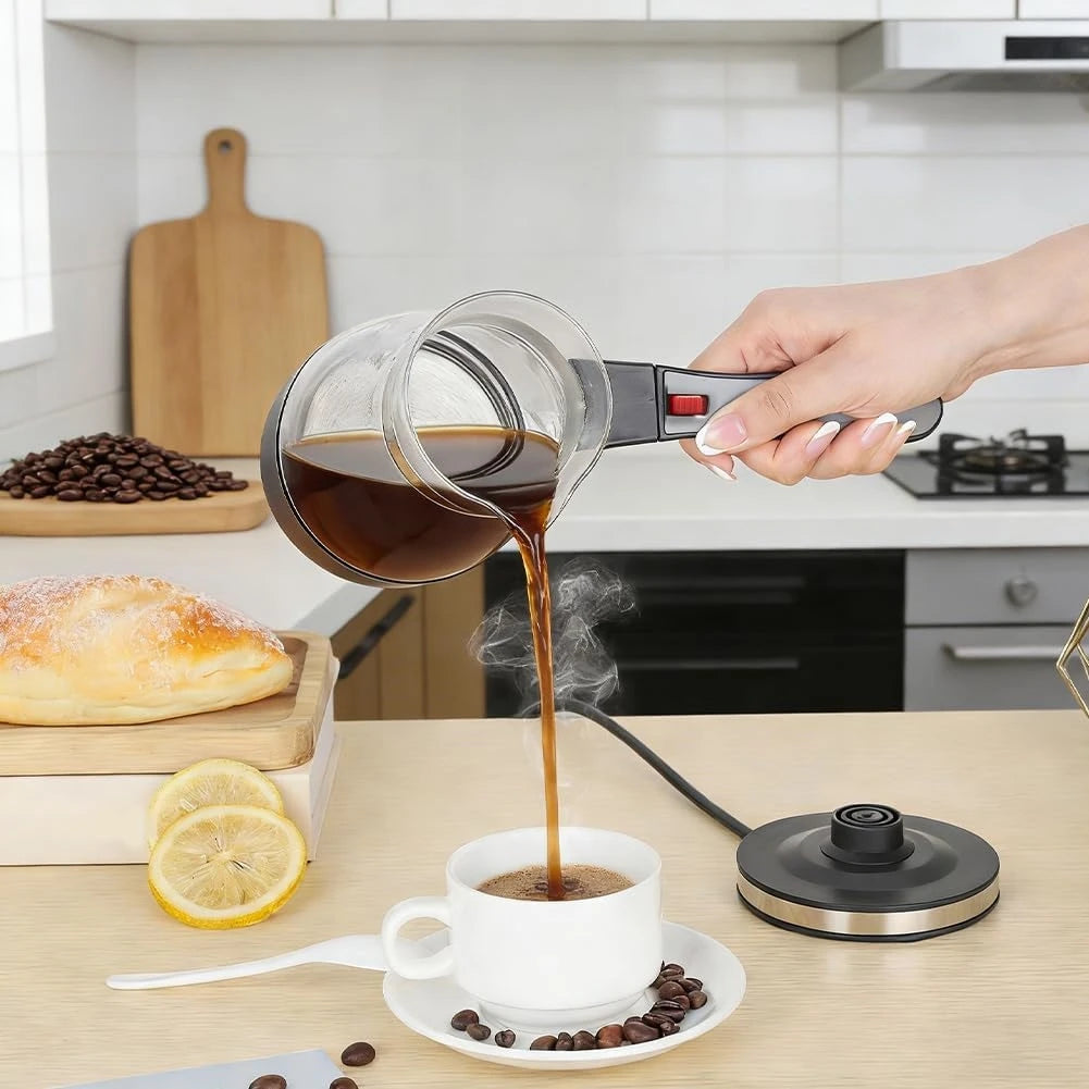 Electric glass Turkish coffee maker pouring fresh coffee into a white cup with a black base on a kitchen counter.