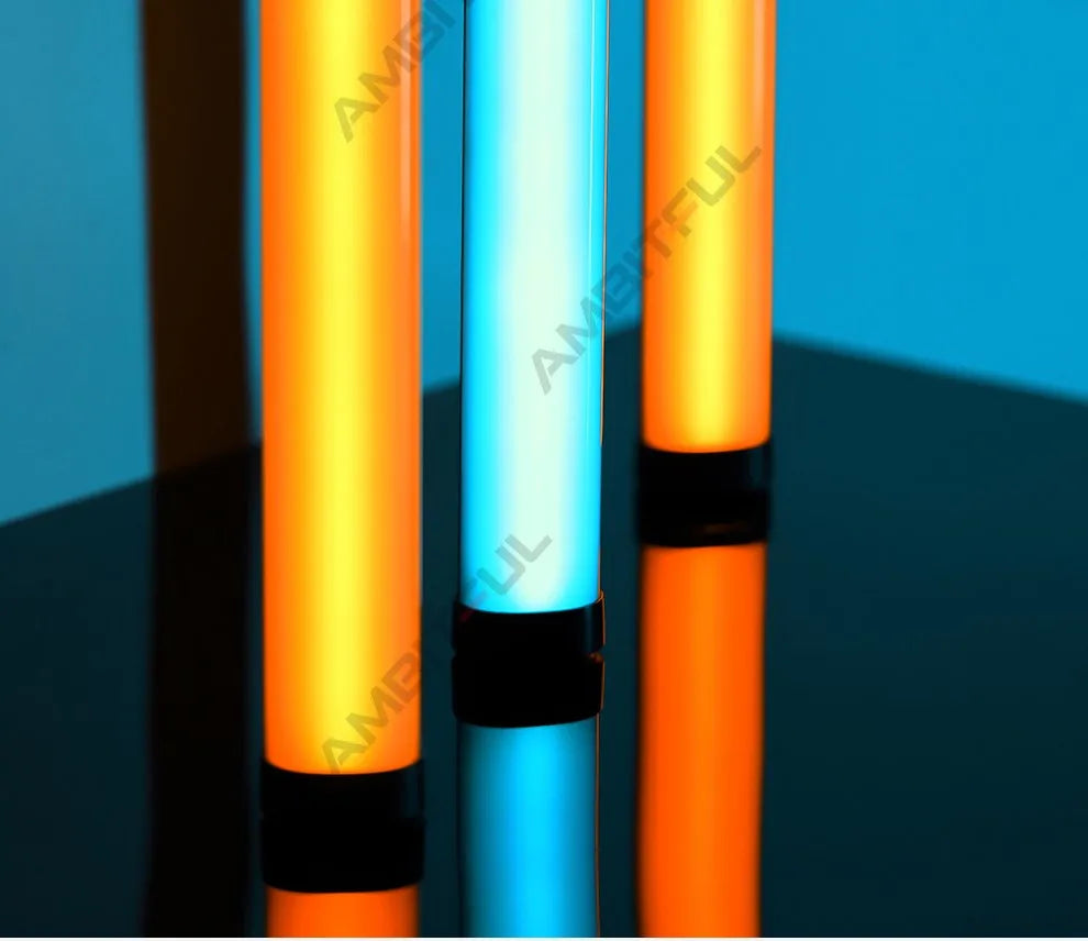 Three vertical LED light tubes with orange and blue glow on a reflective surface for studio and photography lighting.