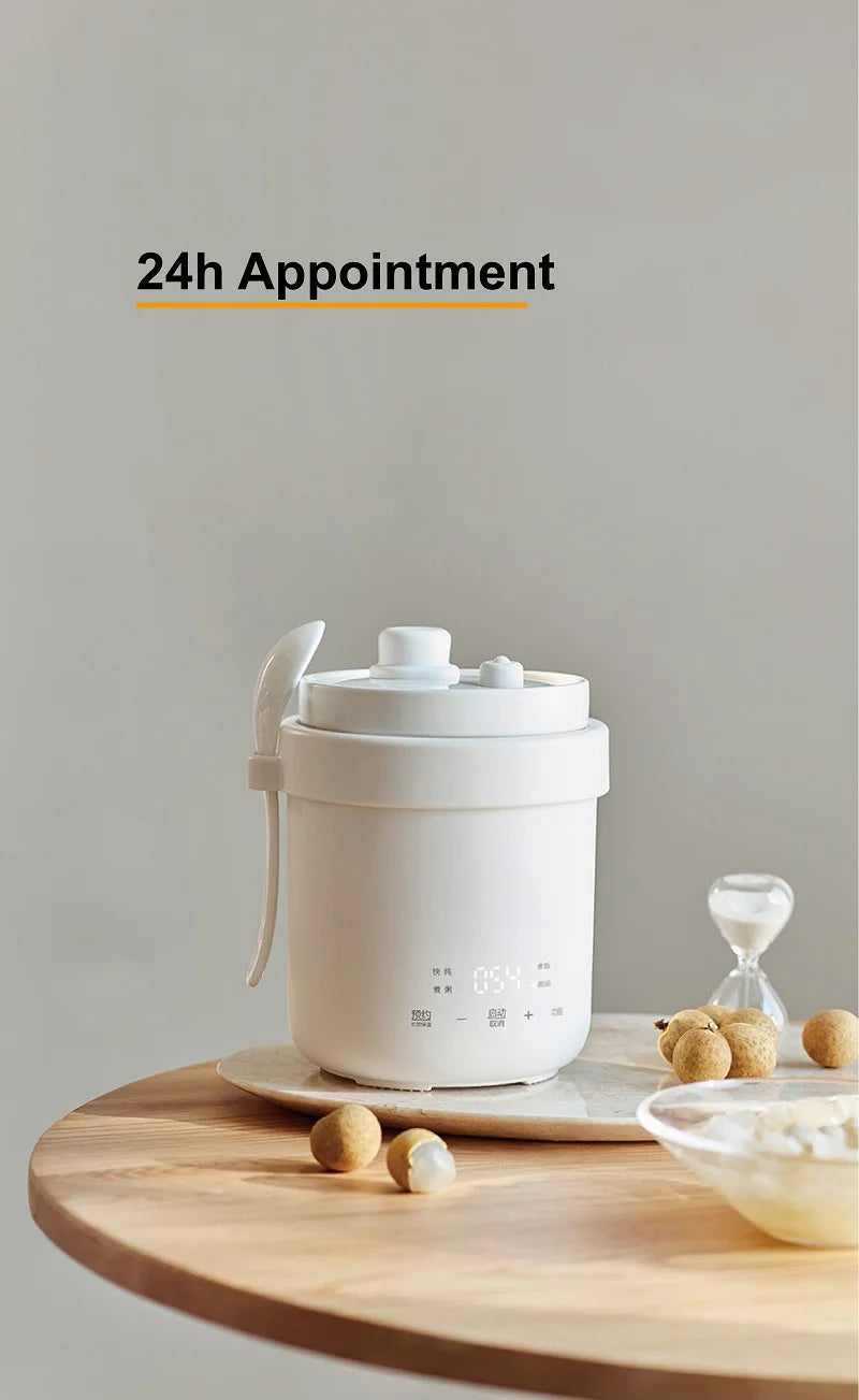 White mini electric rice cooker on round wooden board with lid and handle