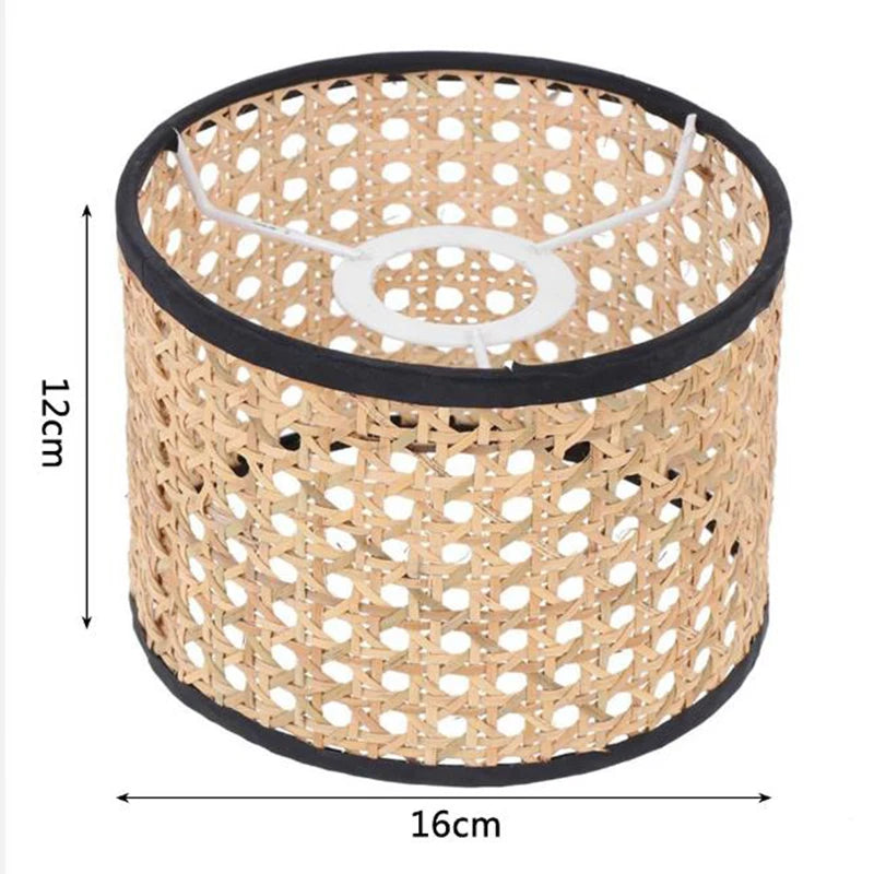 Cylindrical 16x12cm rattan lampshade with black fabric trim and a white metal spider fitter.