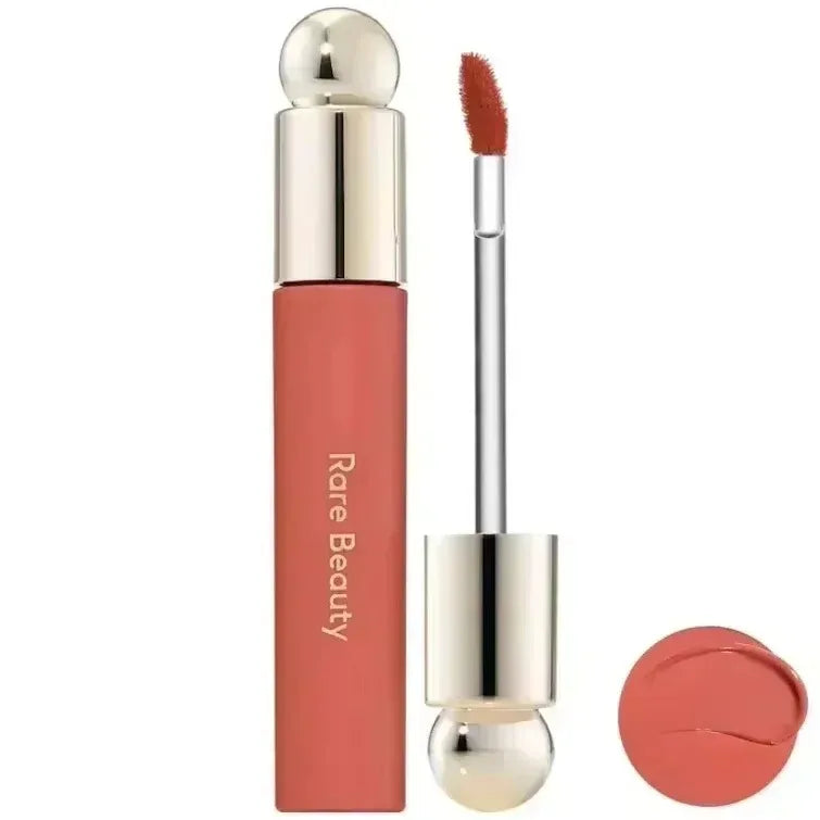 Rare Beauty matte liquid lipstick in a rich coral shade with a smooth, moisturizing texture and applicator wand.