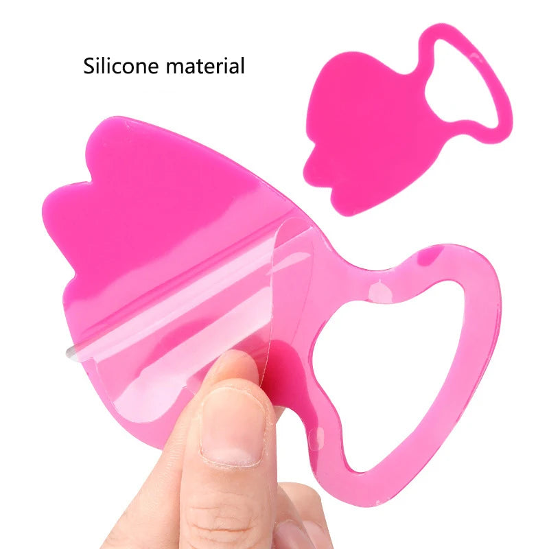Two vibrant pink silicone anti-wrinkle facial patches with cutout designs, one being held by fingers.