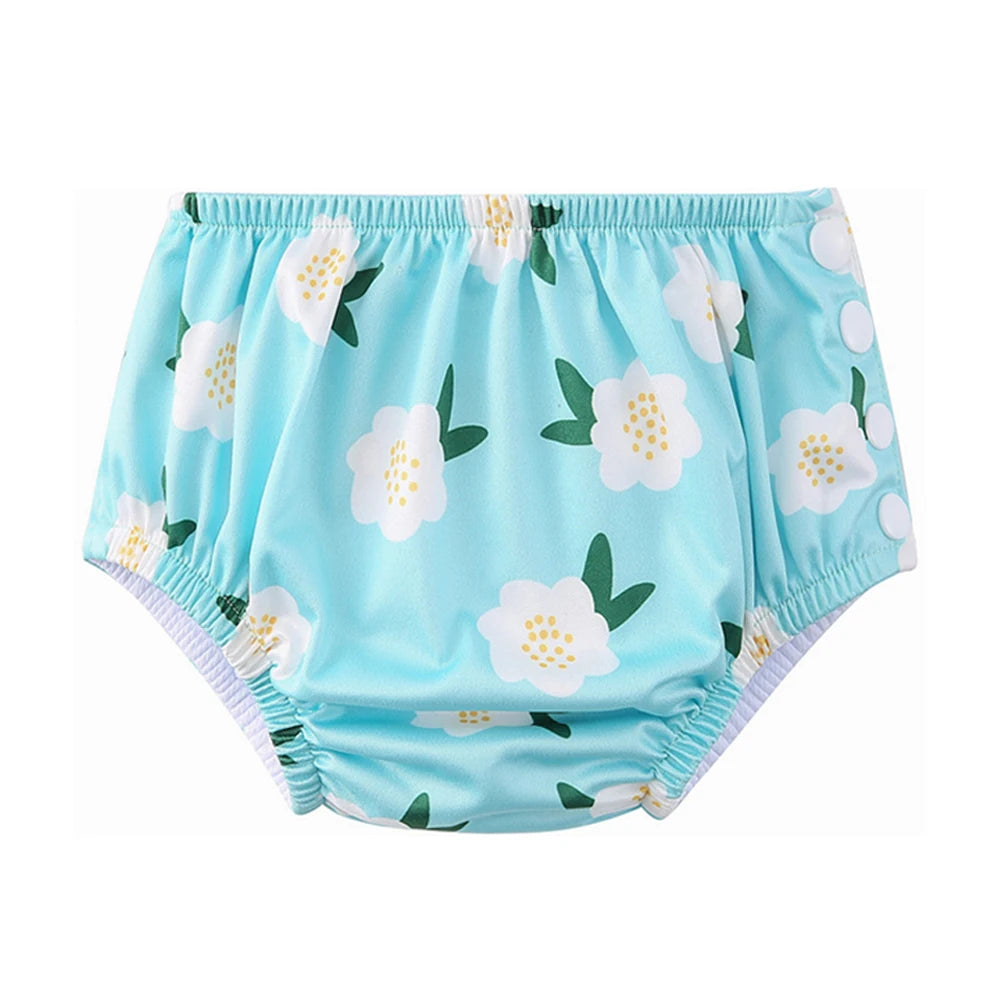 Reusable baby swim diaper in light blue with white floral print and side snap buttons for adjustable fit.