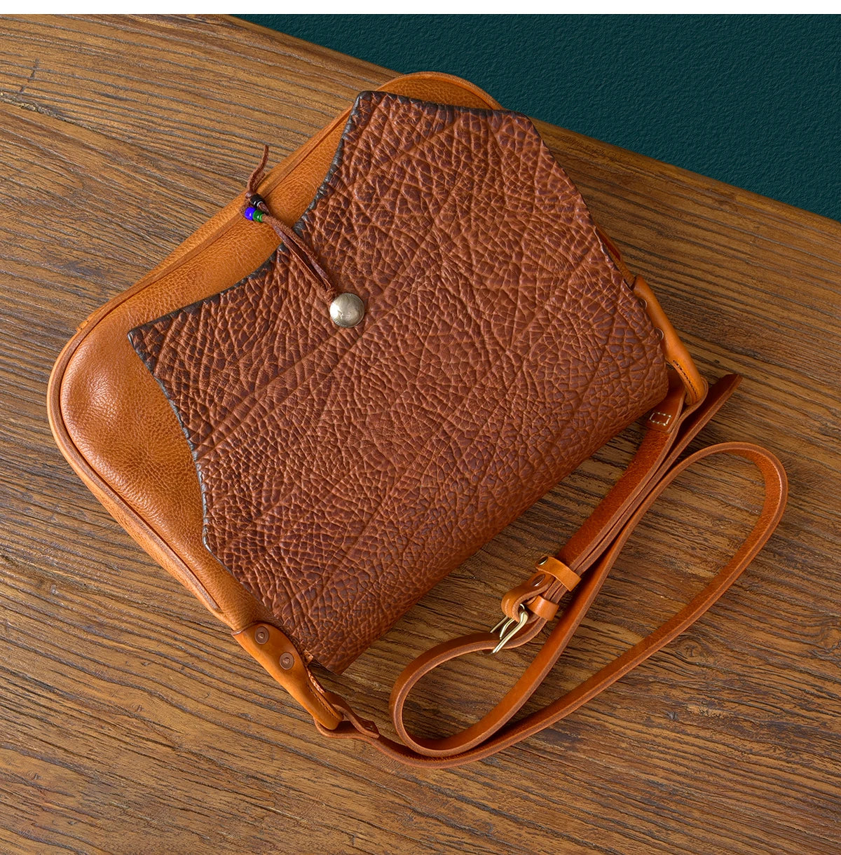 PNDME vintage handmade genuine cowhide leather messenger bag with textured flap, brass snap, and adjustable strap.