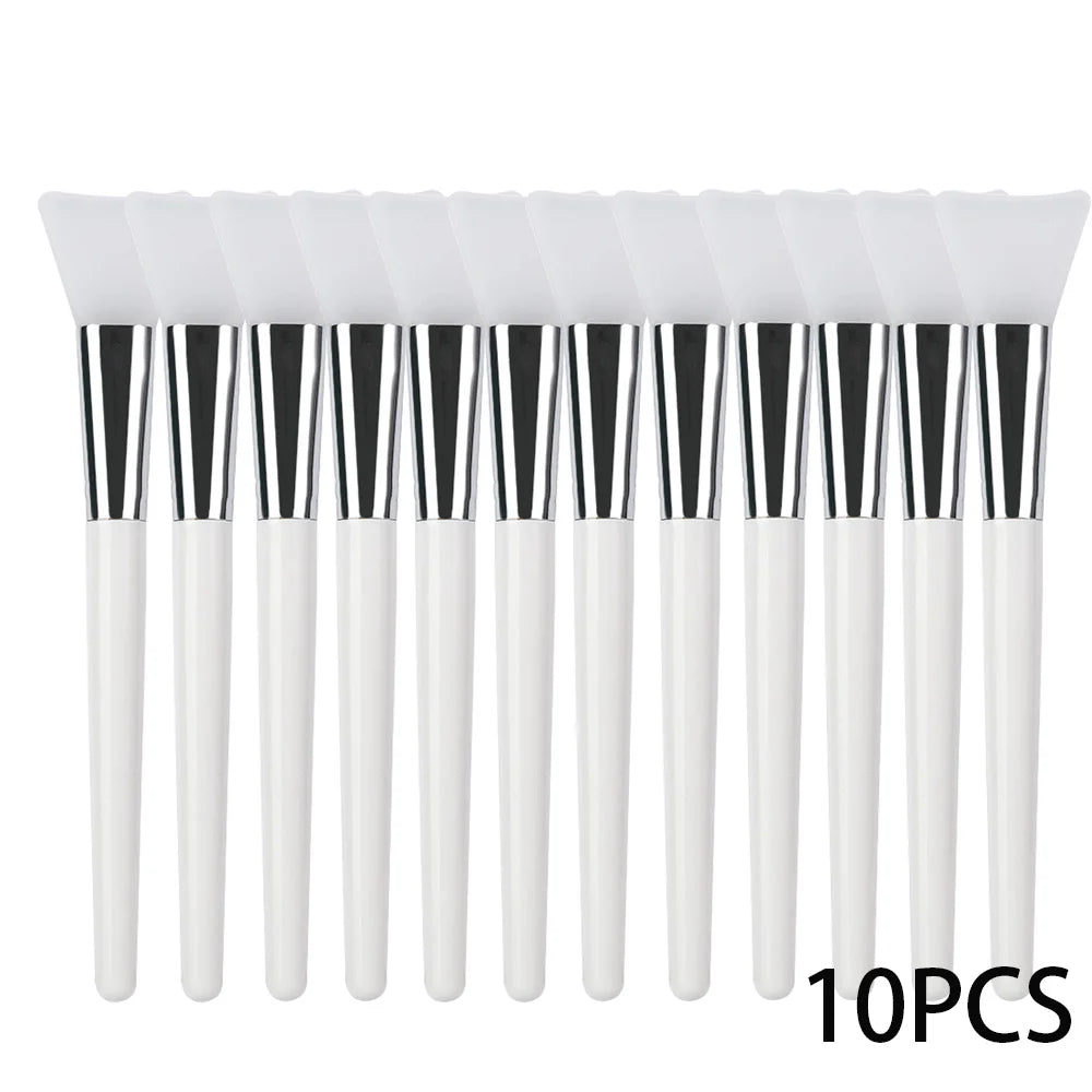 Ten white silicone facial mask brushes with flexible spatula heads, silver ferrules, and smooth white handles.