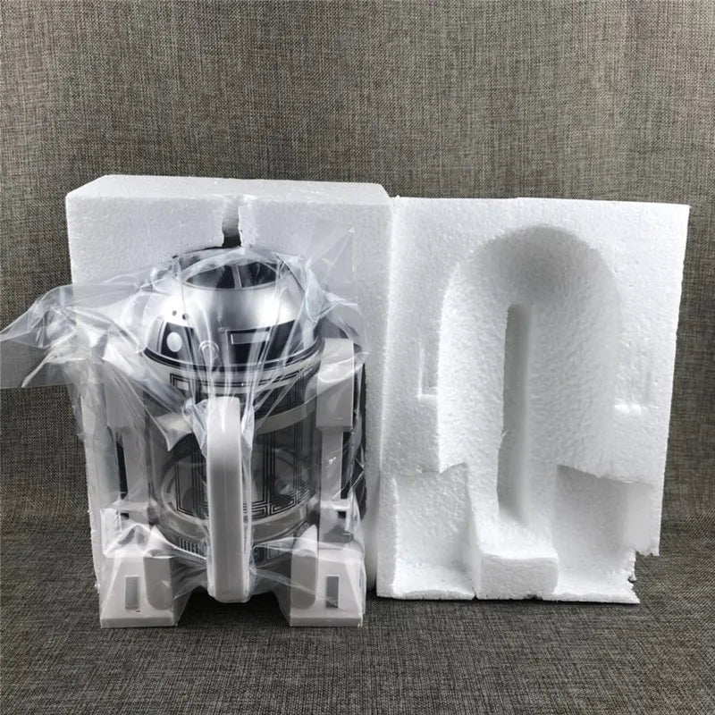 Star Wars R2-D2 French press coffee maker in silver and glass, packaged in protective foam and plastic wrap.