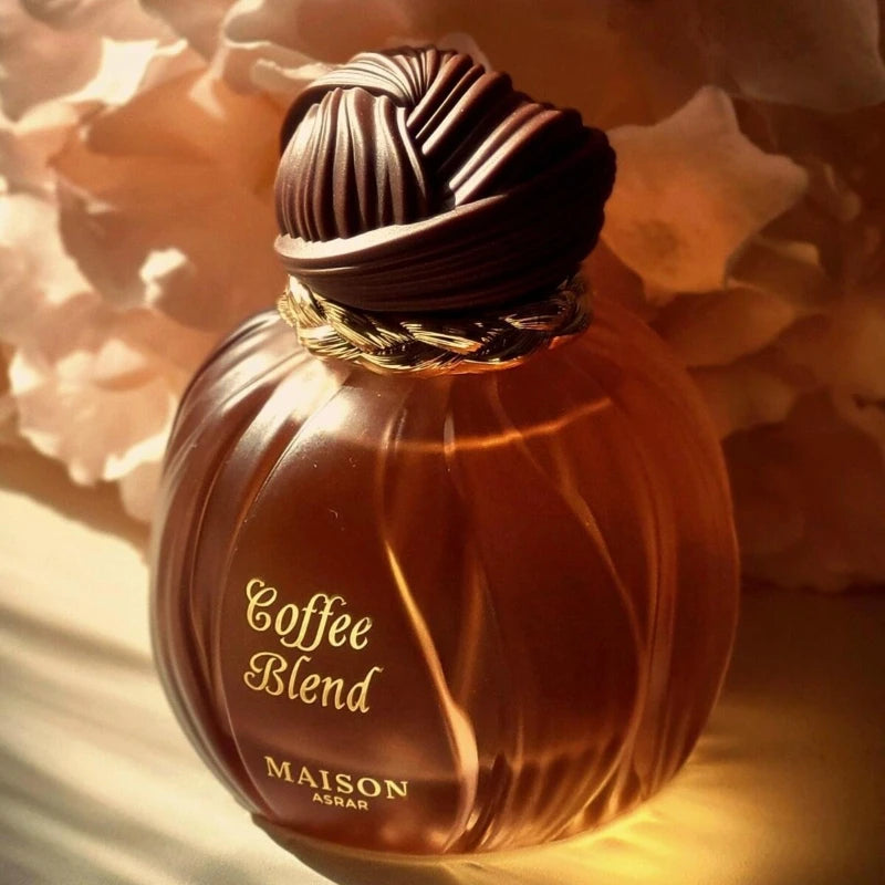 Coffee Blend perfume in a round, ridged amber glass bottle with a dark, knotted cap and gold braided neck detail.