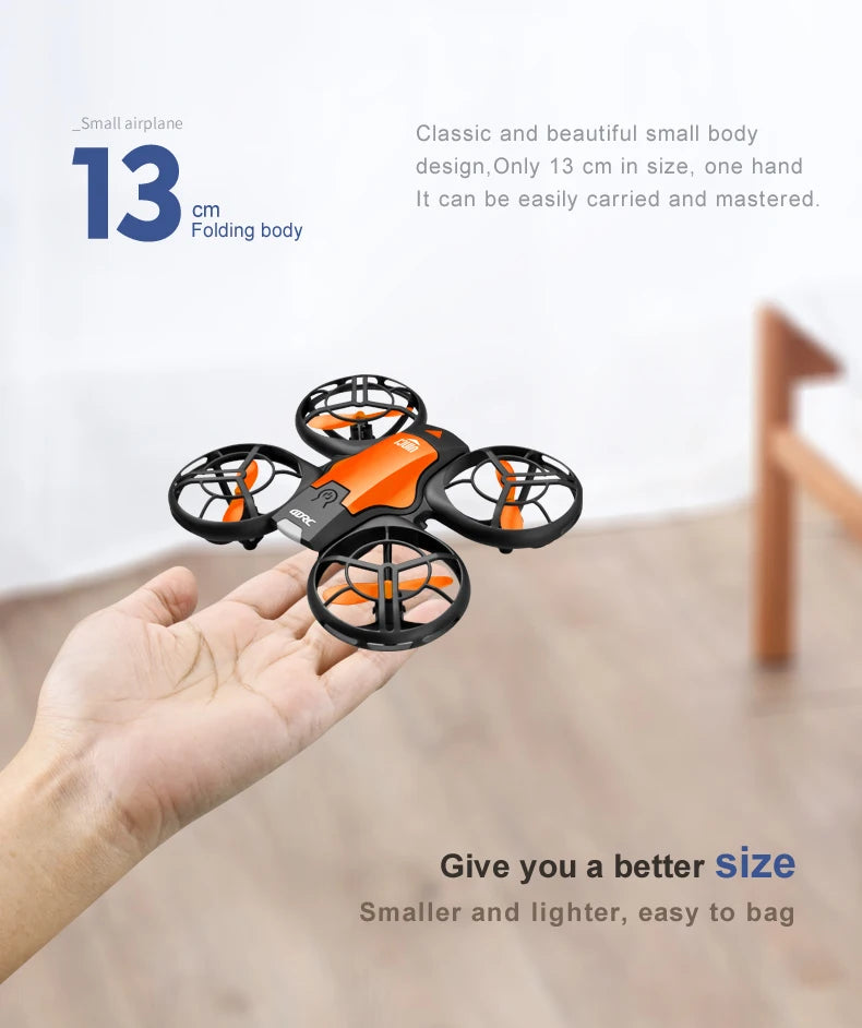 Small 13cm orange and black RC drone with protective propeller guards, held in a hand for scale.