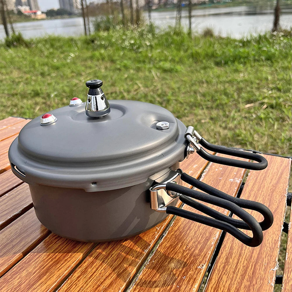 Gray pressure cooker with vented lid knob and curved folding handles on wooden deck
