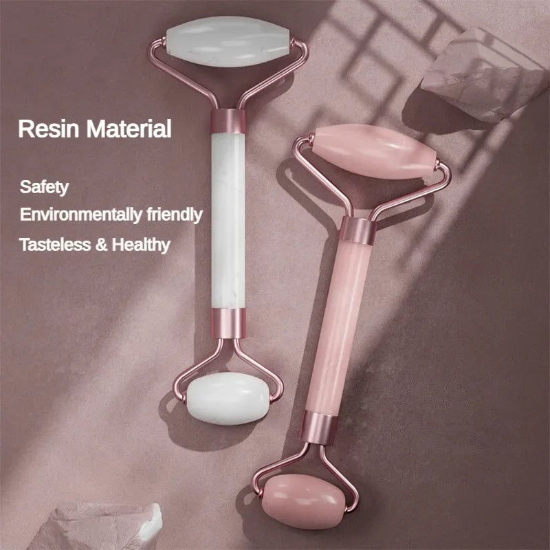 Two resin facial massage rollers with rose gold metal frames, one in white and one in soft pink.