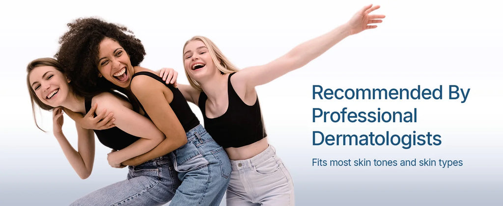 Three diverse, happy young women in black tank tops and denim jeans laughing together against a white background.