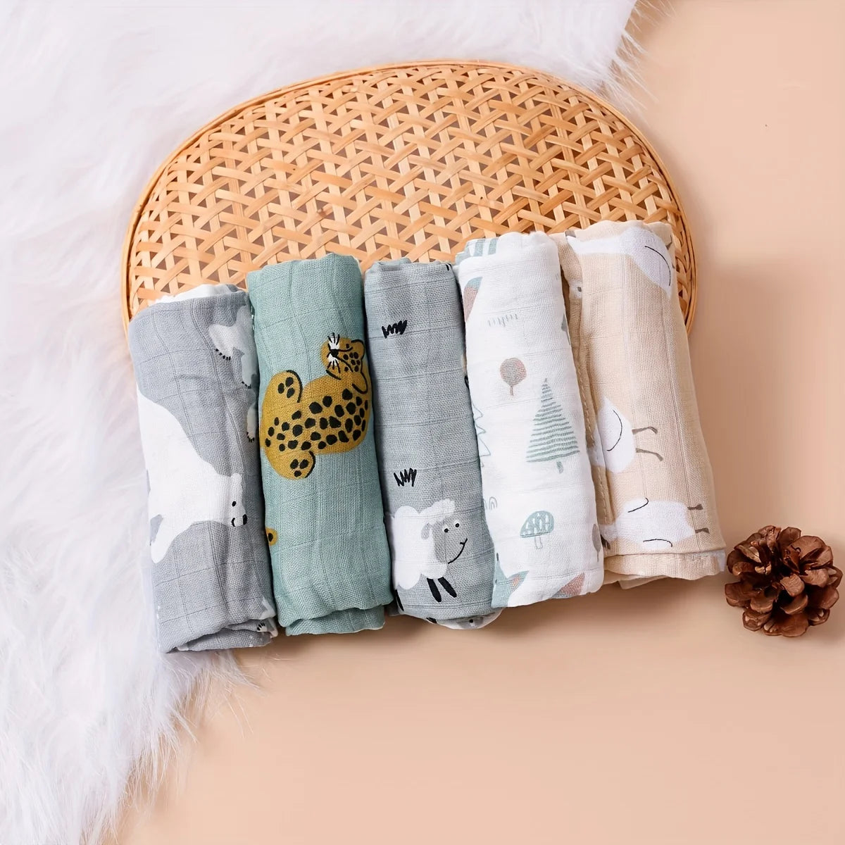 Set of 5 baby care muslin swaddle blankets with cute animal and nature prints in a woven basket.