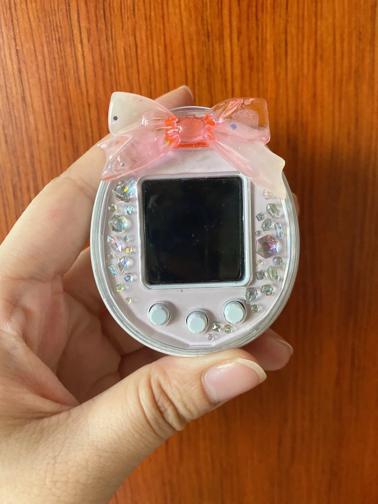Tamagotchi Uni case with pink bow and crystals. Protective silicone heart dust plug for custom virtual pet style.