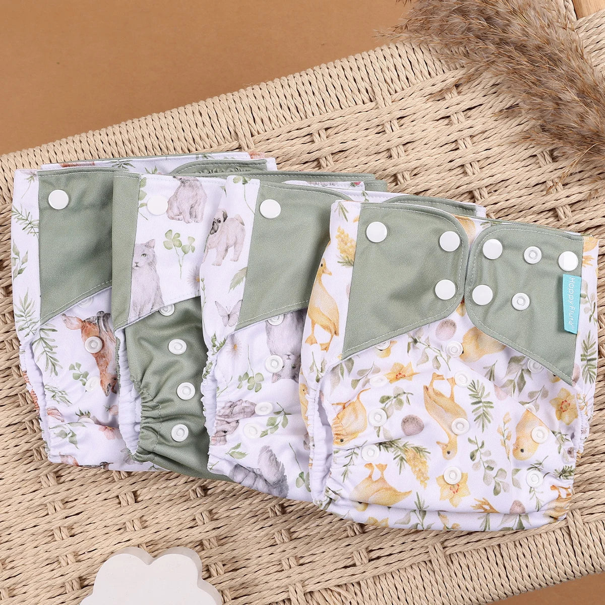 Happy Flute reusable cloth diapers with woodland animal, duck, and cat prints, featuring adjustable snap buttons.