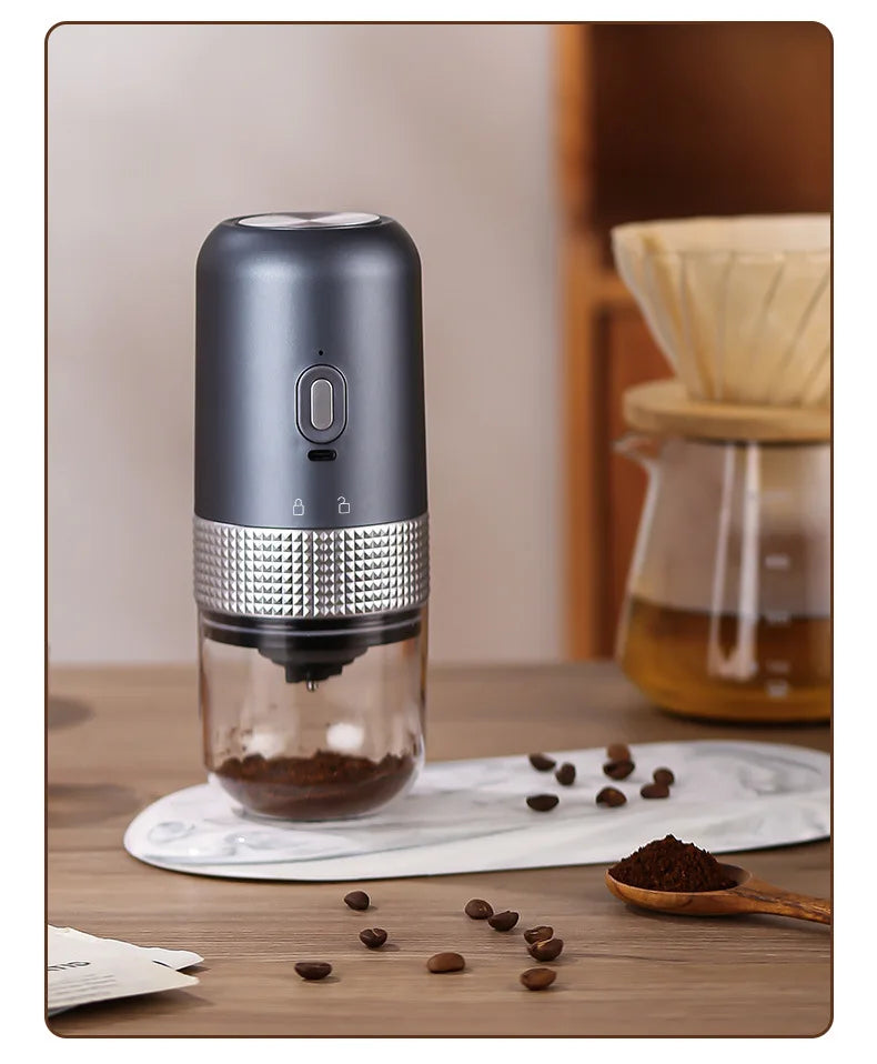 Portable electric coffee grinder in matte dark gray with a textured silver grip and clear grounds container.