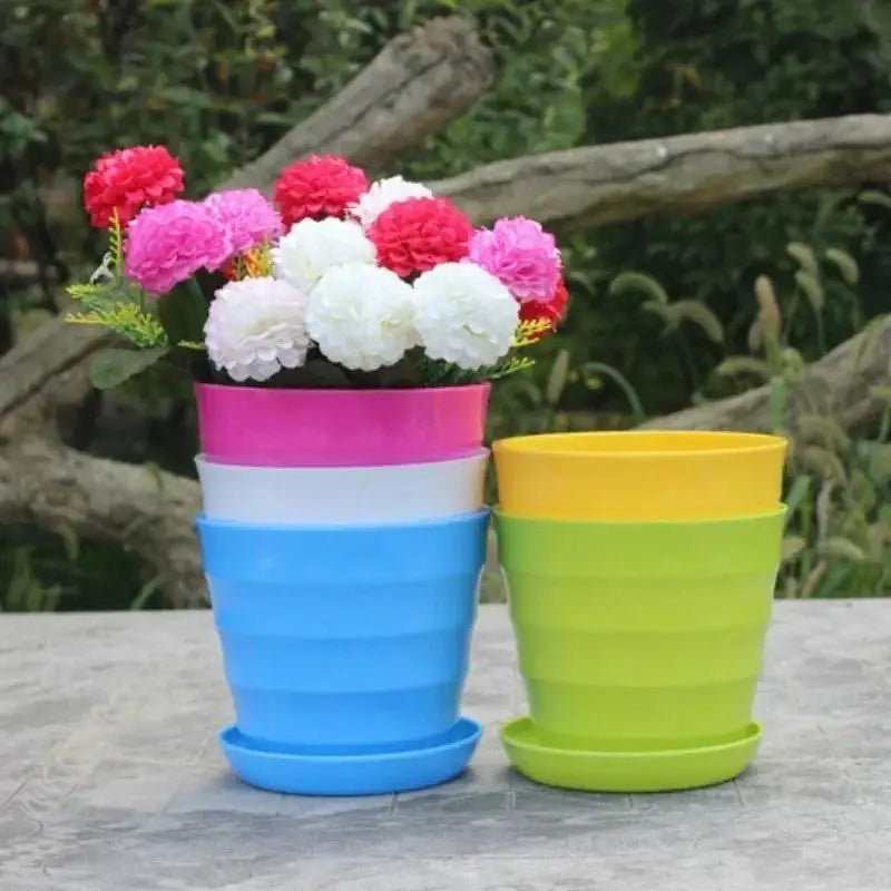 Stacked multi-color plastic flower pots with pink, white, and yellow flowers