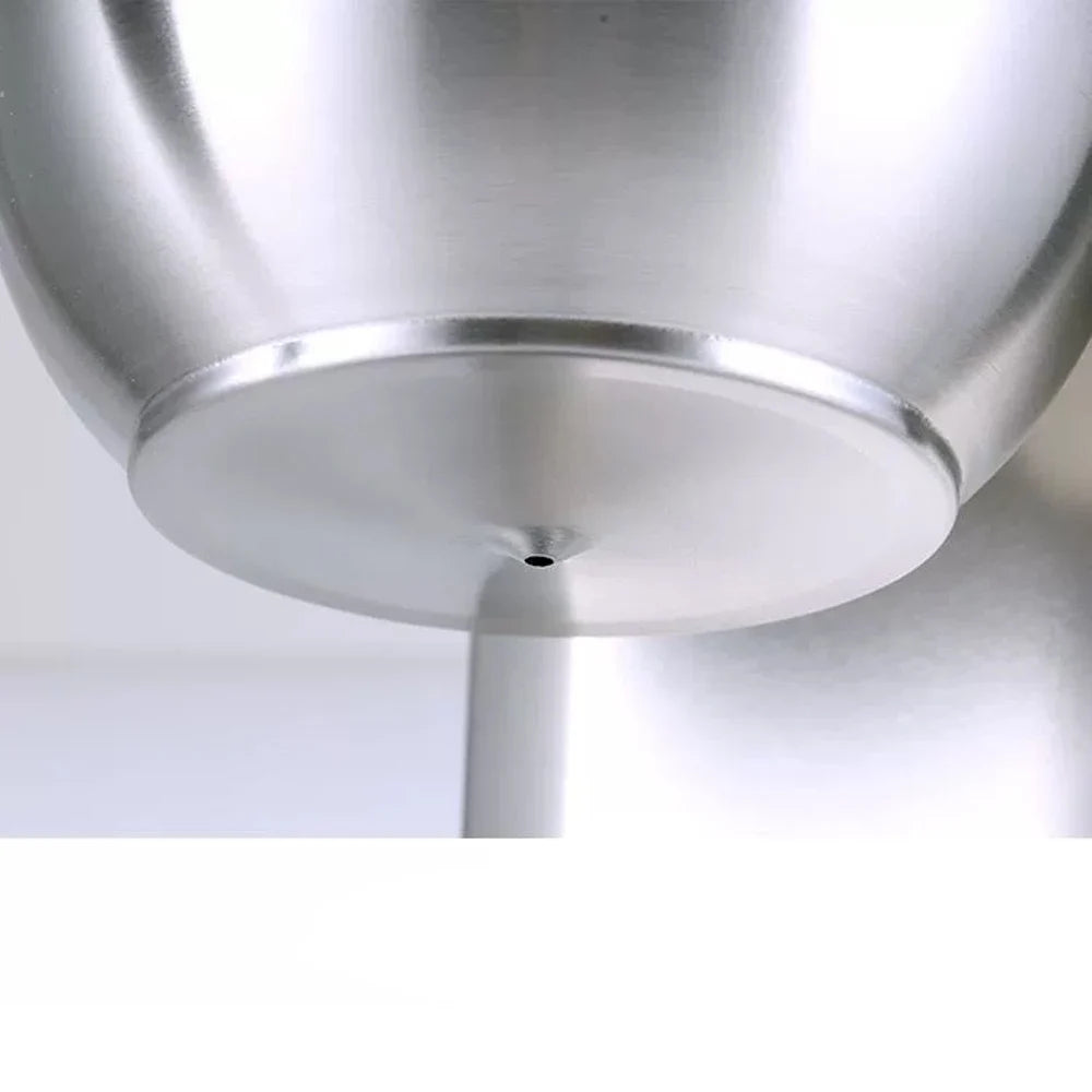Close-up of a brushed stainless steel coffee dripper base with a single precision flow hole for consistent brewing.