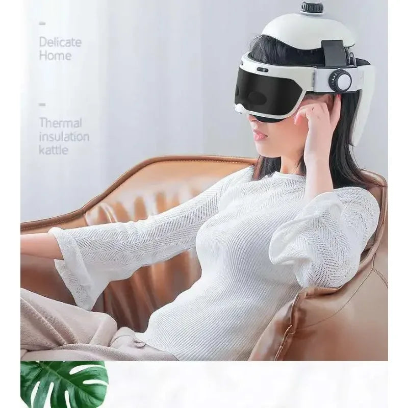 White integrated head and eye massager helmet for home therapy, worn by a woman relaxing on a brown leather chair.