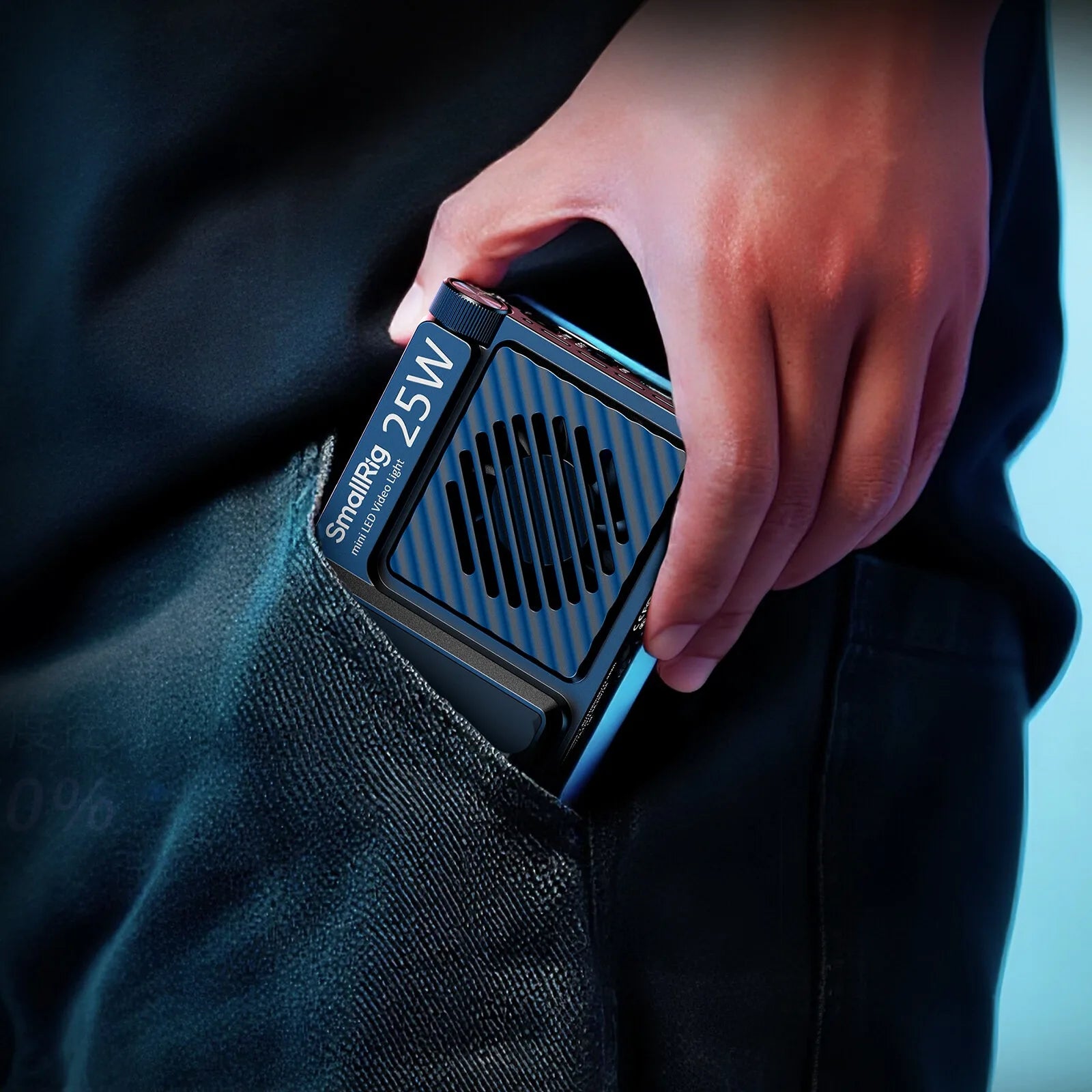 Small 25W LED video light with a black, rectangular, vented metal body held in a person's jeans pocket.