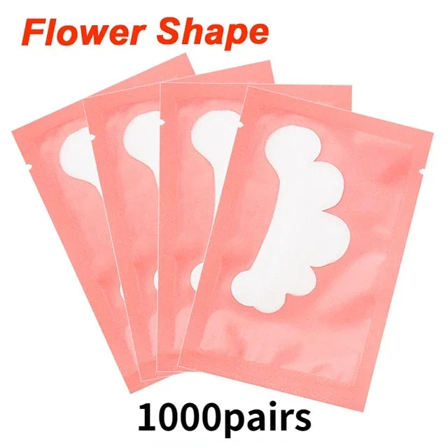 Flower-shaped gel eyelash extension under-eye pads in pink individual sachets for professional lash application.