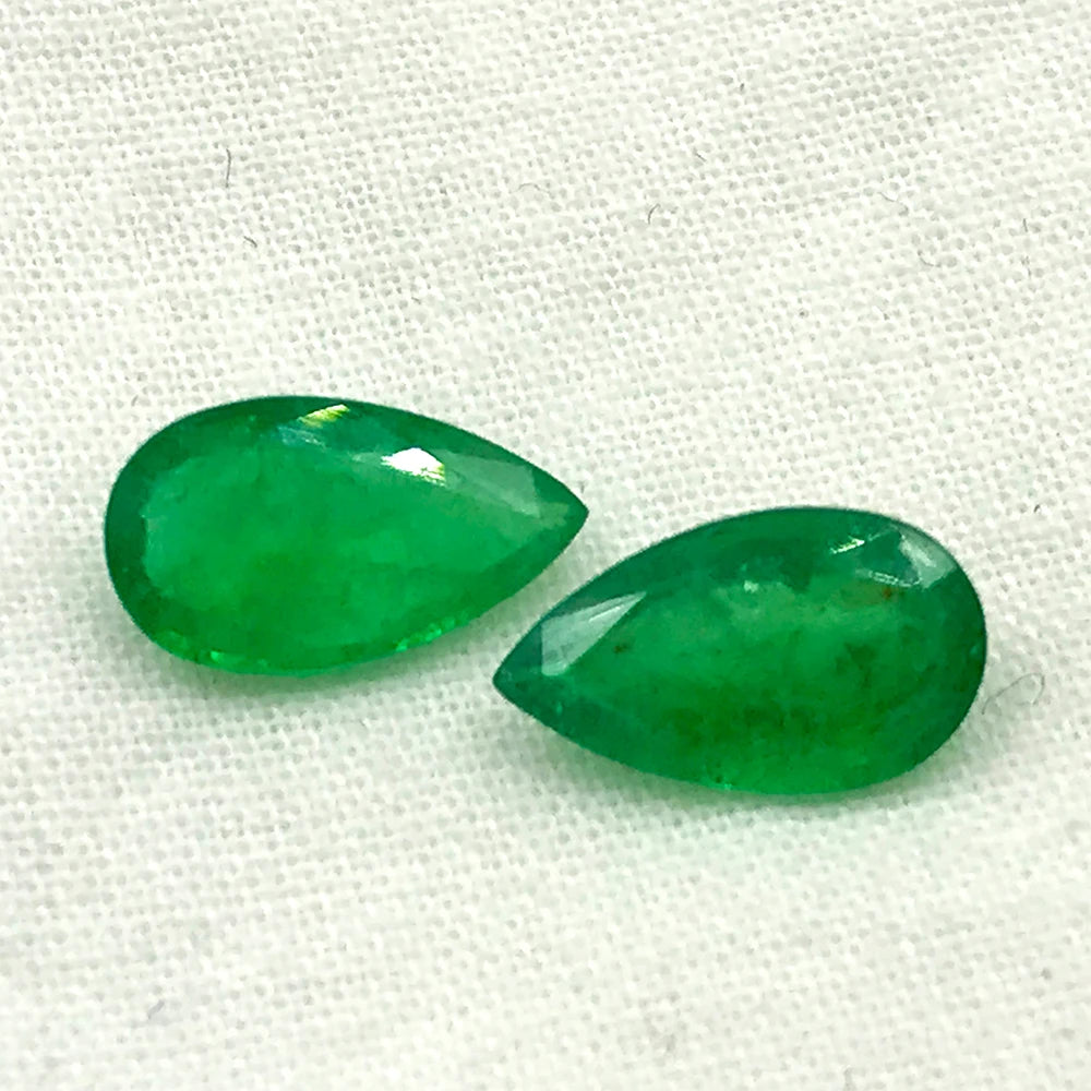 Close-up pair of green teardrop gemstone cabochons with reflective highlights