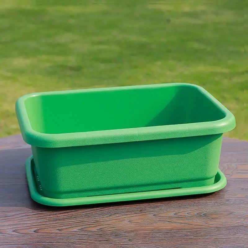 Green rectangular planter pot with matching green tray on wooden table