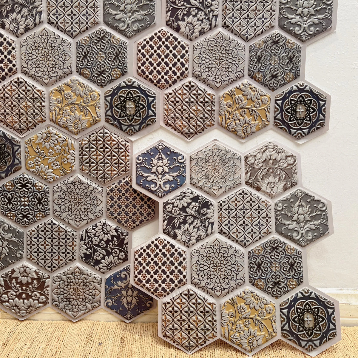 Peel-and-stick hexagon backsplash tiles with black, gray, and gold patterned designs