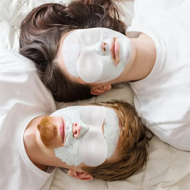 A man and woman lying down with white ultrathin cotton eye masks over their eyes and green clay face masks.