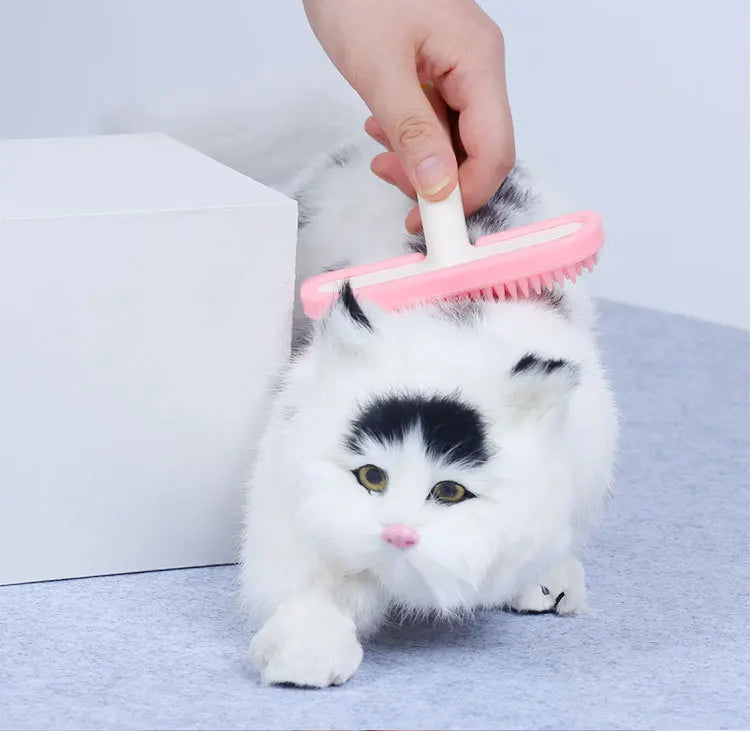 Pink silicone pet grooming comb brushing a small cat for gentle hair removal and tangle-free fur care.