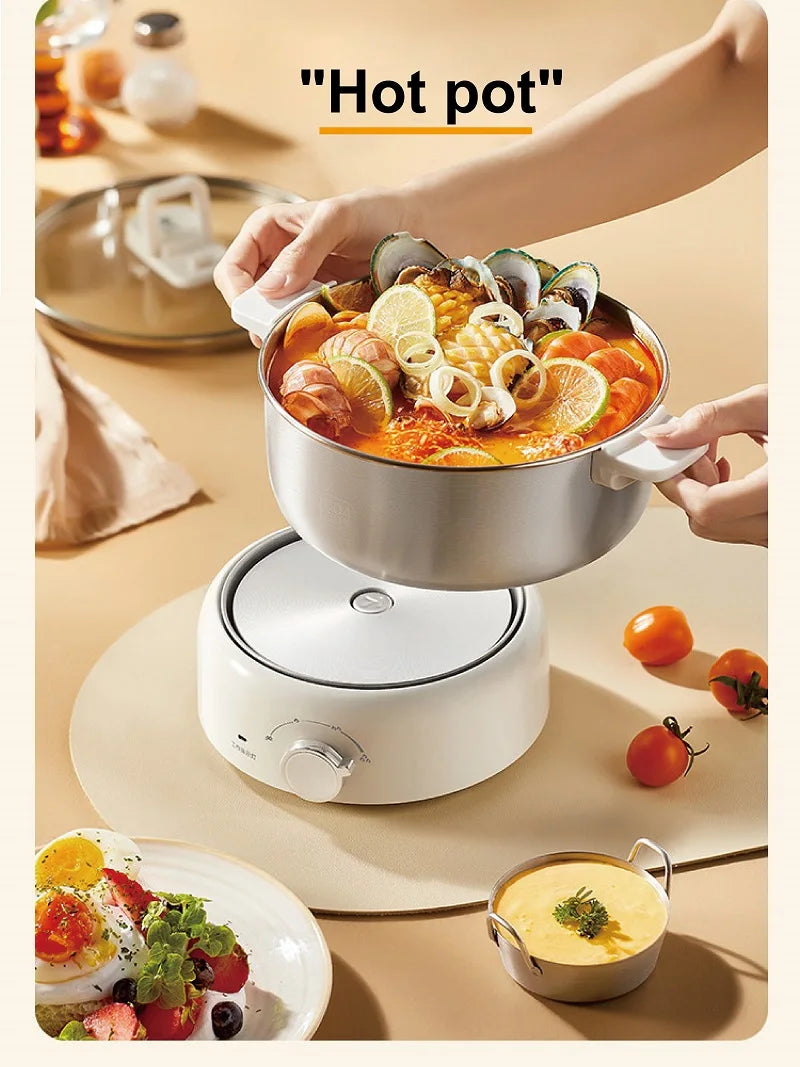 Stainless hot pot on white electric base with lid, hands holding side handles